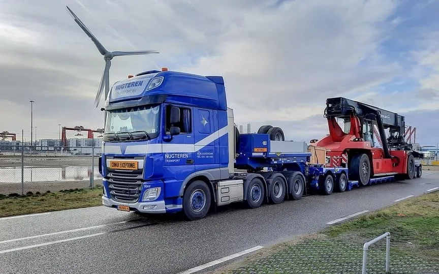 Dieplader van Nugteren Transport met reachstacker en windmolen op de achtergrond